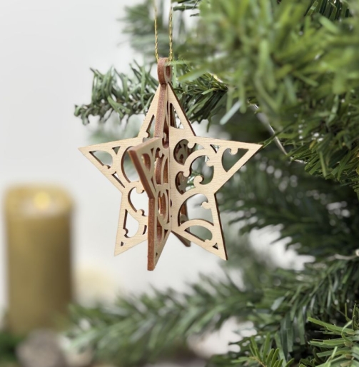 Dreidimensionaler Weihnachtsanhänger Stern aus Holz vor einer goldenen Kerze – filigraner Christbaumschmuck und kleines Weihnachtsgeschenk.