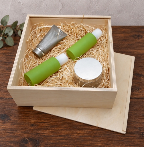 Genussbox 24 x 24 x 9 cm aus Birkensperrholz mit Kosmetikprodukten auf Holzwolle
