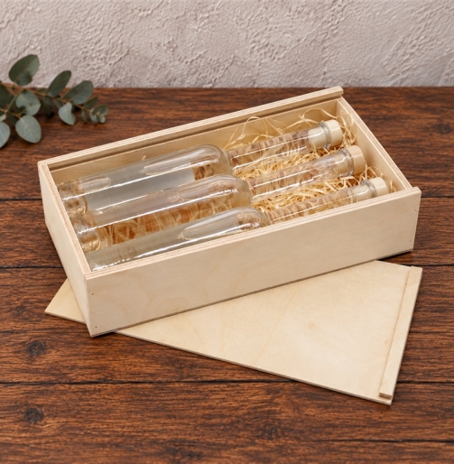 Offene Mini-Holzkiste 26 x 13 x 4,5 cm mit drei Glasflaschen auf Holzwolle
