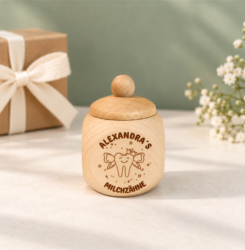 Milchzahndose aus Holz mit Zahnfee und Namen vor einem Geschenk