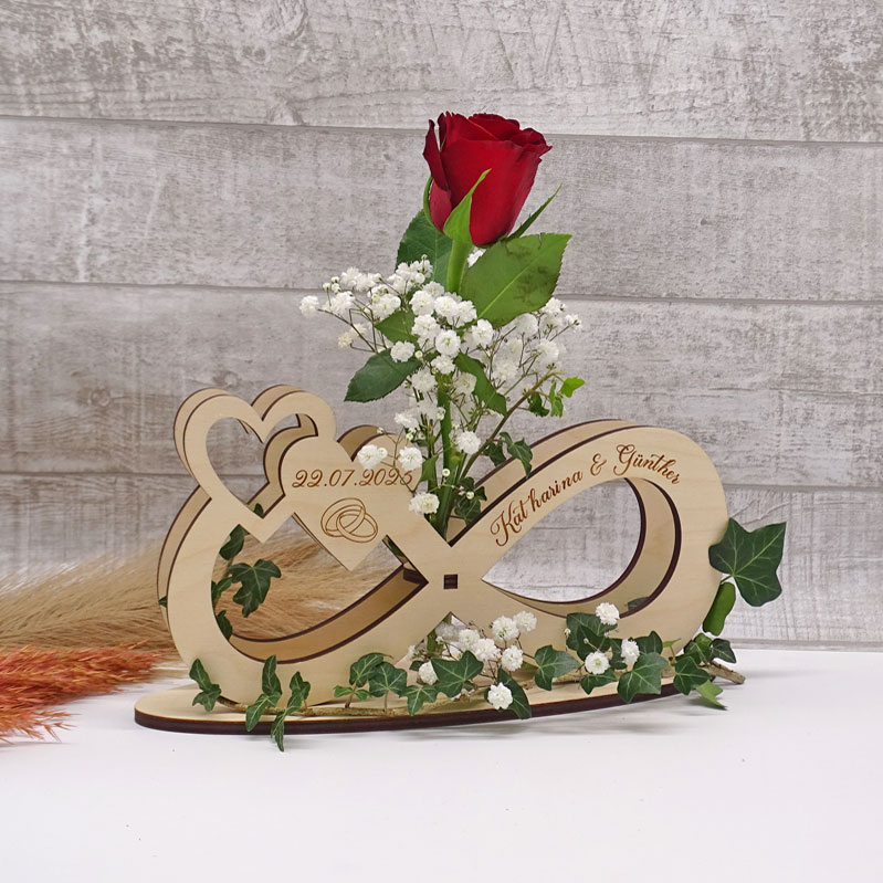 Unendlichkeitszeichen aus Holz mit Namen Katharina & Günther und Datum graviert, mit roter Rose und Schleierkraut im Blumenröhrchen